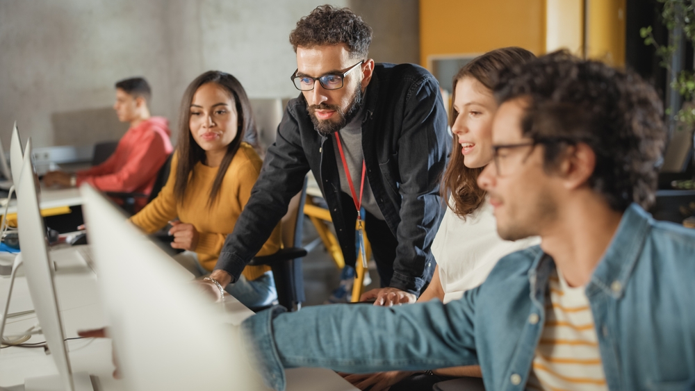Students and apprentices collaborating with a mentor in a modern workplace